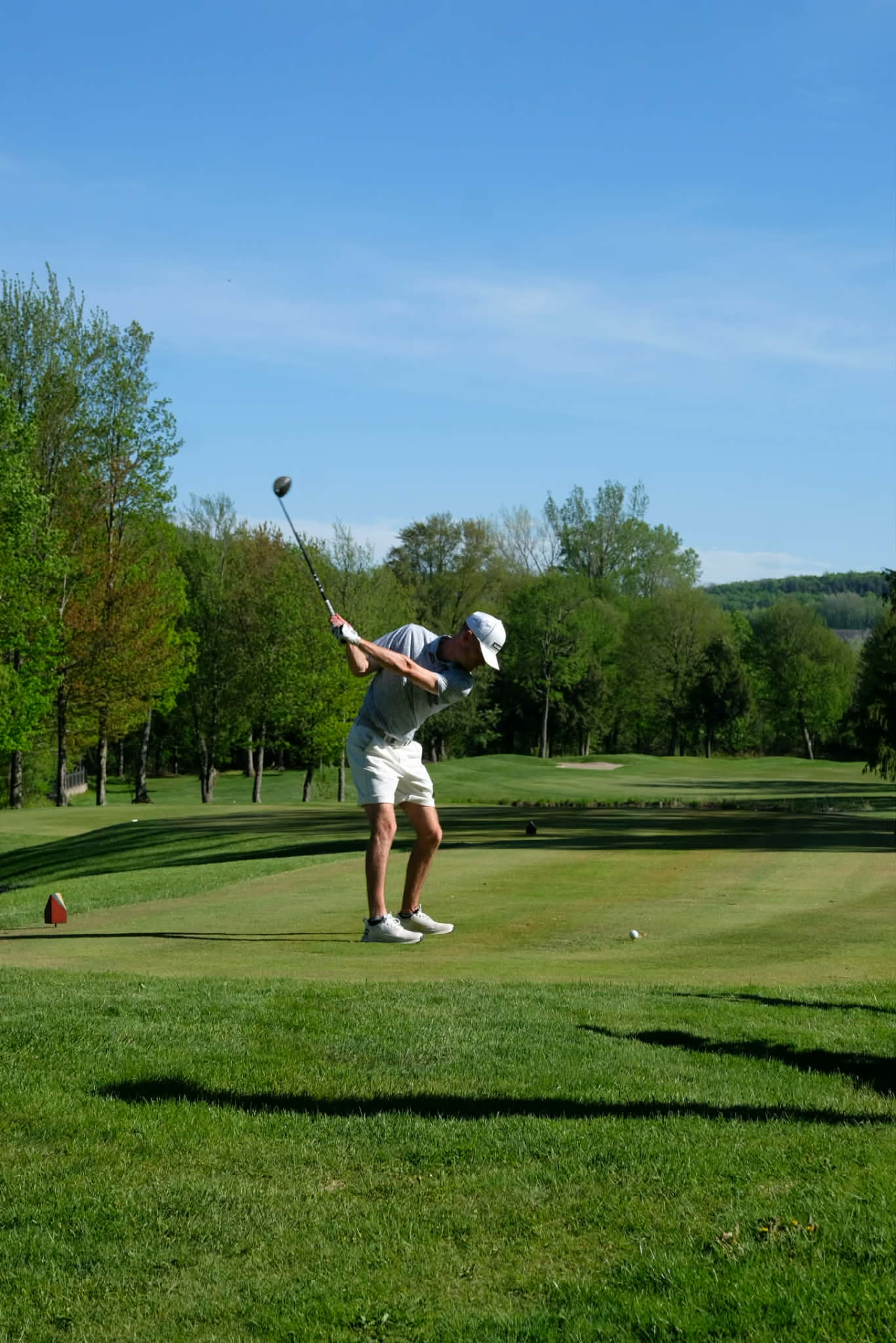 Olivier, professionnel de golf, au sommet de son élan avec un driver sur un parcours